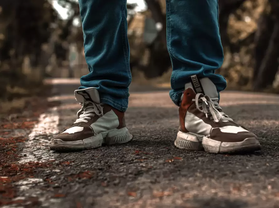 person in blue denim pants and brown and white sneakers