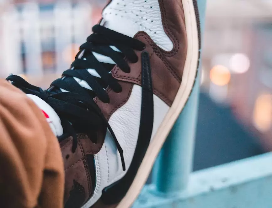 crop person in stylish sneakers admiring city from building roof